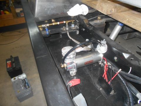 1992 Ford Bronco - Close-up view of an air compressor system and associated plumbing, with two batteries nearby.