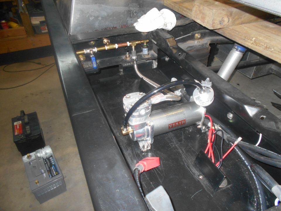 Air compressor and brass plumbing with blue valve, next to two car batteries