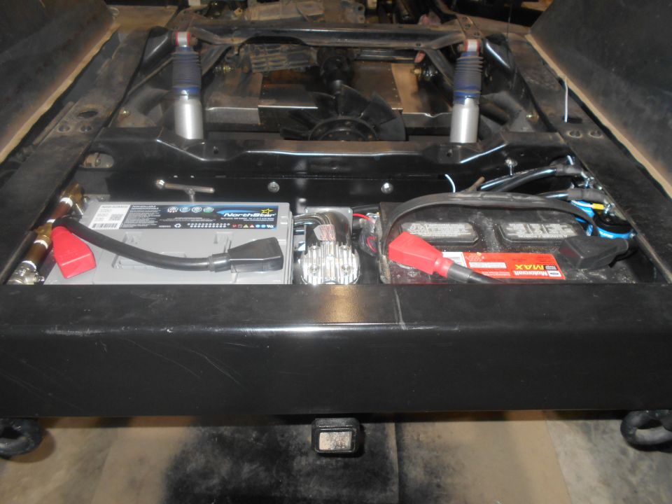 Vehicle chassis with two batteries, wiring, and shocks visible
