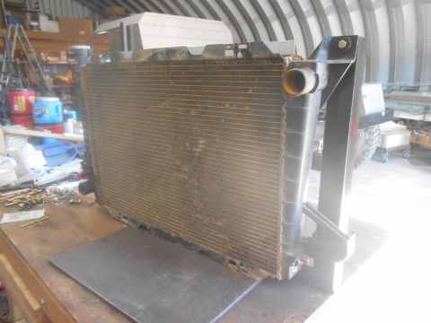 1992 Ford Bronco - A large, dirty radiator is displayed on a workbench, likely removed from a vehicle for repair or replacement.