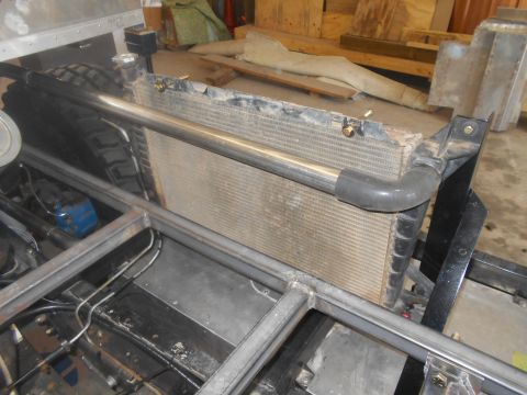 1992 Ford Bronco - Close-up view of a vehicle's radiator and custom metal frame, with workshop debris in the background.