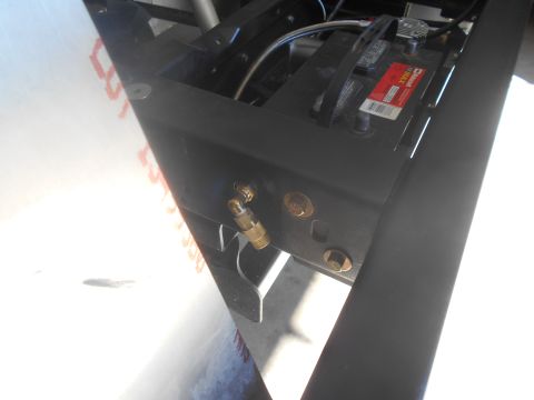 1992 Ford Bronco - A close-up view of a vehicle's battery and an attached air fitting on its frame.