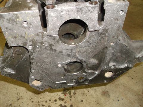 1969 Ford Mustang - Close-up view of a gray engine block with visible bolt holes and openings, resting on a concrete surface.