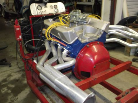 1970 Ford Torino - A V8 engine assembly is shown on a red stand, chrome exhaust headers and a blue engine block.