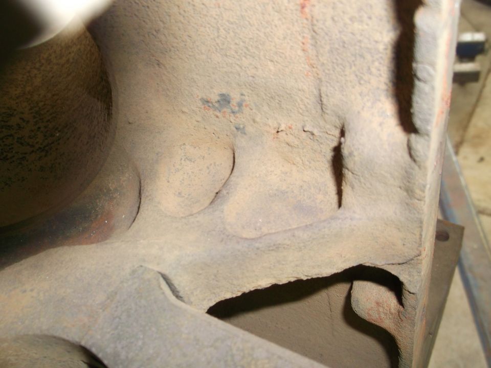Close-up of rough cast iron engine block interior with dust and pitting.