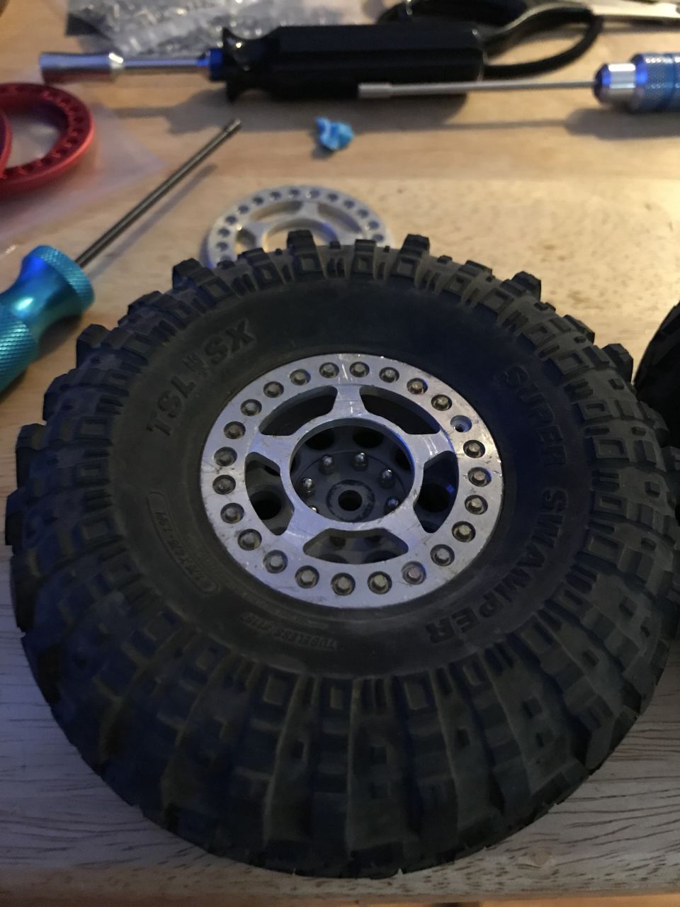 RC car tire with silver beadlock wheel, tools in background