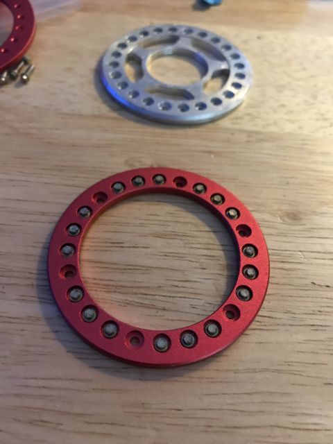 1989 Ford Bronco - A red circular metal part with multiple small silver bolts is shown in the foreground, with a silver circular metal part with similar bolt…