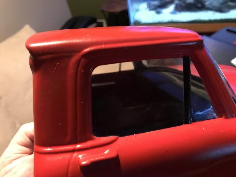 1989 Ford Bronco - Close-up side view of the red cab of a classic truck, showing the window frame and a portion of the roof.