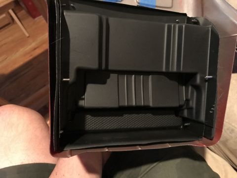 1989 Ford Bronco - A black plastic interior part is shown, possibly a storage bin or tray, with visible mounting screws. The part has molded ribs and a textur…