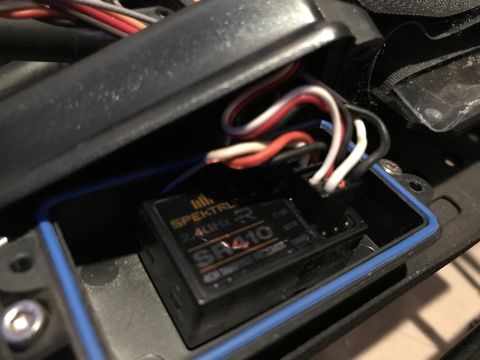 1989 Ford Bronco - A Spektrum SR410 2.4GHz 4CH Surface Receiver is visible inside a black plastic enclosure with a blue gasket. The receiver has several wires…