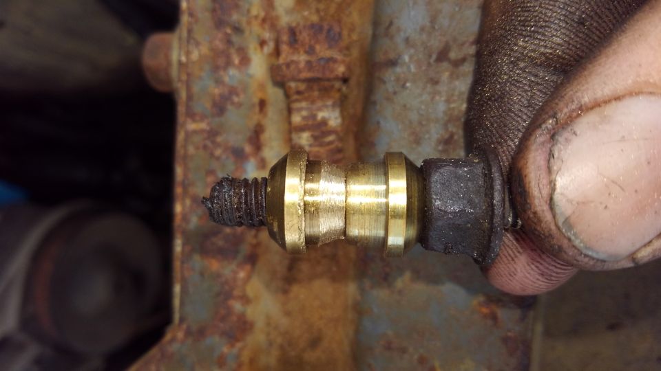 Greasy brass fitting on rusty bracket with a dirty thumb and fingers