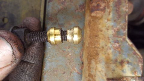 1988 Ford Bronco - A close-up shot shows a hand holding a bolt with two brass fittings. The fittings appear to be part of a brake line or fuel line connection…