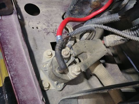 1996 Ford Bronco - A close-up view of a starter solenoid mounted to a dusty engine bay component. A thick red cable connects to the solenoid, alongside severa…