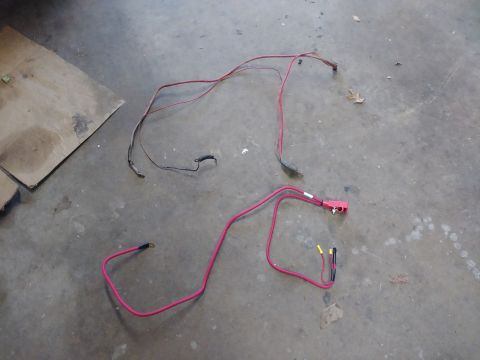1996 Ford Bronco - Two red automotive wiring harnesses are laid out on a concrete floor. One harness has a red connector with two yellow wire ends and one bla…