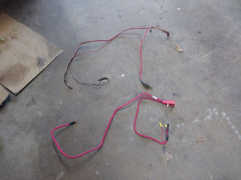 Two red automotive wiring harnesses on a concrete floor.