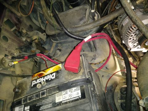 1996 Ford Bronco - A close-up view of a vehicle's engine bay shows a DieHard Gold car battery with red and black cables connected to its terminals, along with…