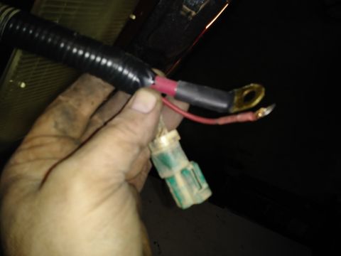 1996 Ford Bronco - A hand holds a wiring harness with a green connector and two ring terminals. The harness is covered in black corrugated tubing.