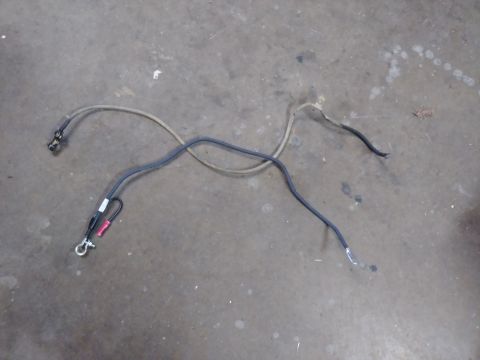 1996 Ford Bronco - A pair of automotive battery cables are laid out on a concrete floor. One cable is black with red and white connectors, and the other is a…