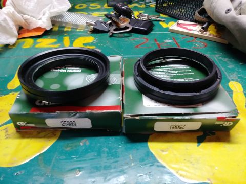 1996 Ford Bronco - Two black rubber radial seals are shown sitting on top of their respective green and white cardboard boxes. The boxes have part numbers pri…