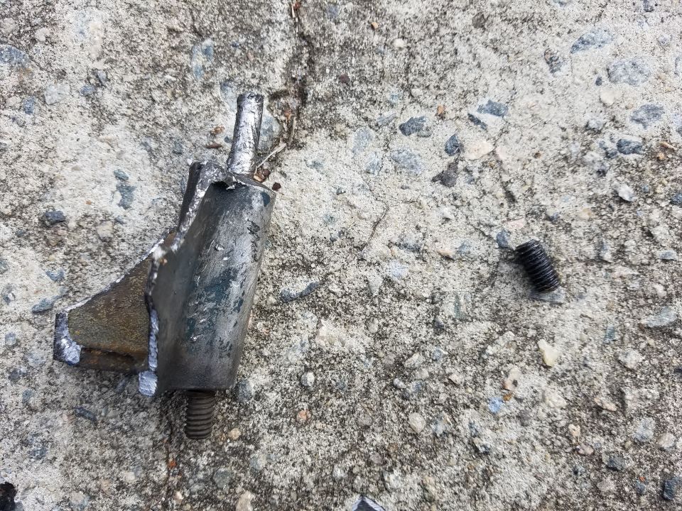 Broken metal bracket with bolt and separate screw on concrete