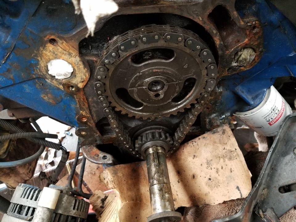 Close-up of engine timing chain and gears on a blue V8 engine block.