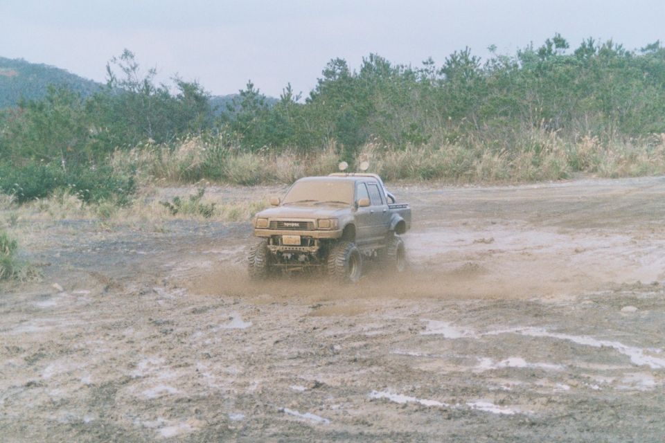 Mud-covered Toyota pickup truck with large tires driving through a muddy field
