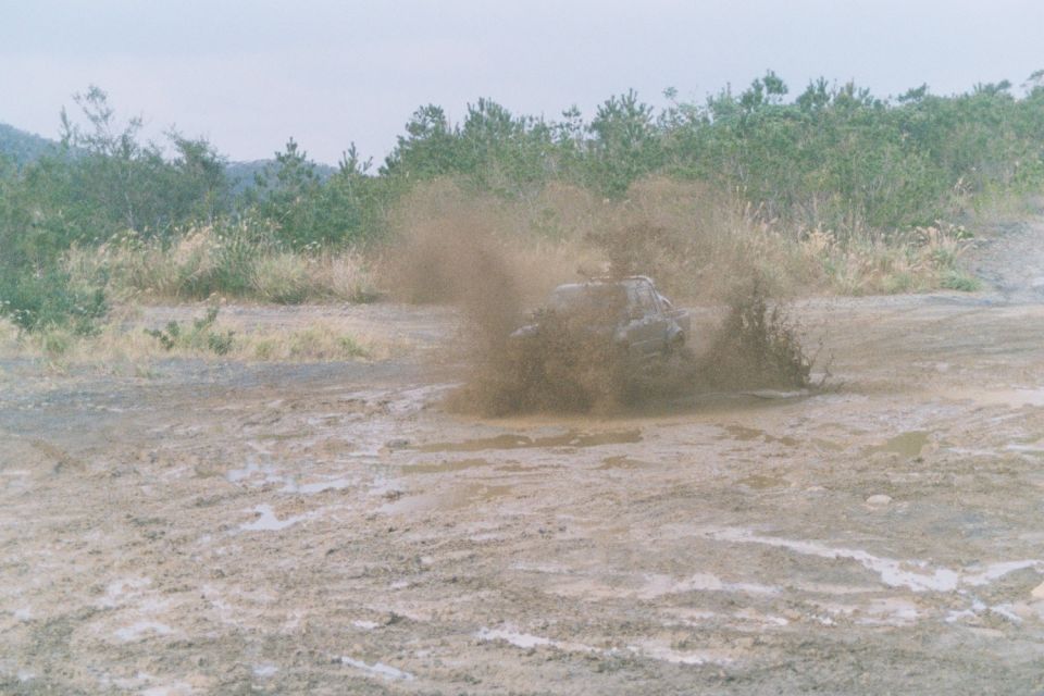Truck driving through a muddy area, kicking up a lot of spray