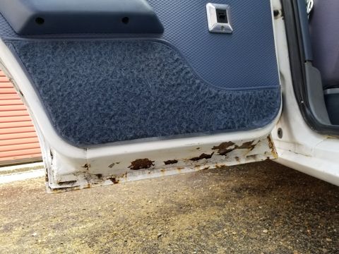 2001 Ford Crown Victoria - Photograph of a car's interior door panel and rusted lower door edge; not a technical document.