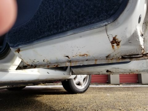 2001 Ford Crown Victoria - Photograph of a corroded rocker panel and lower door of a car; not a technical document.
