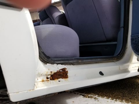 2001 Ford Crown Victoria - Photograph of a car door opening with rusted sill and blue cloth seats; not a technical document.