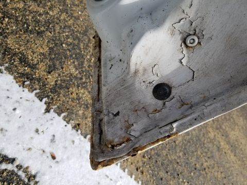 2001 Ford Crown Victoria - Photograph of a rusty, peeling metal body panel corner; not a technical document.