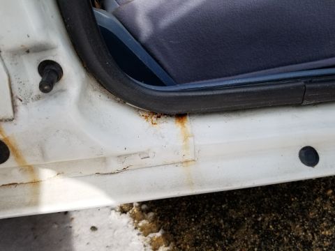 2001 Ford Crown Victoria - Photograph of a rusted door sill and blue interior trim; not a technical document.
