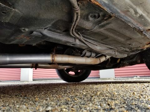2001 Ford Crown Victoria - Photograph of a vehicle underbody exhaust pipe and floor pan; not a technical document.
