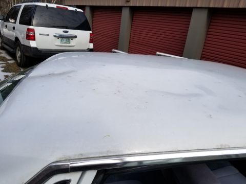 2001 Ford Crown Victoria - Photo of the roof of a white Ford LTD sedan parked outside red storage units, not a technical document.