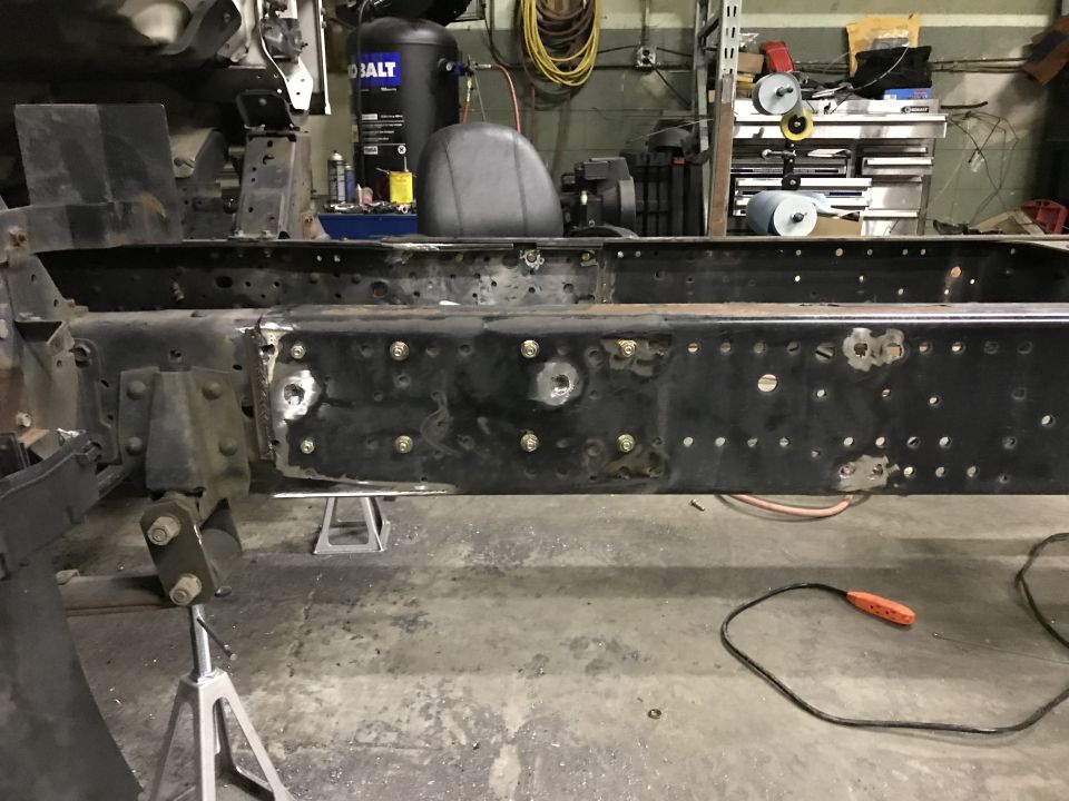 Modified truck frame on jack stands in a workshop.