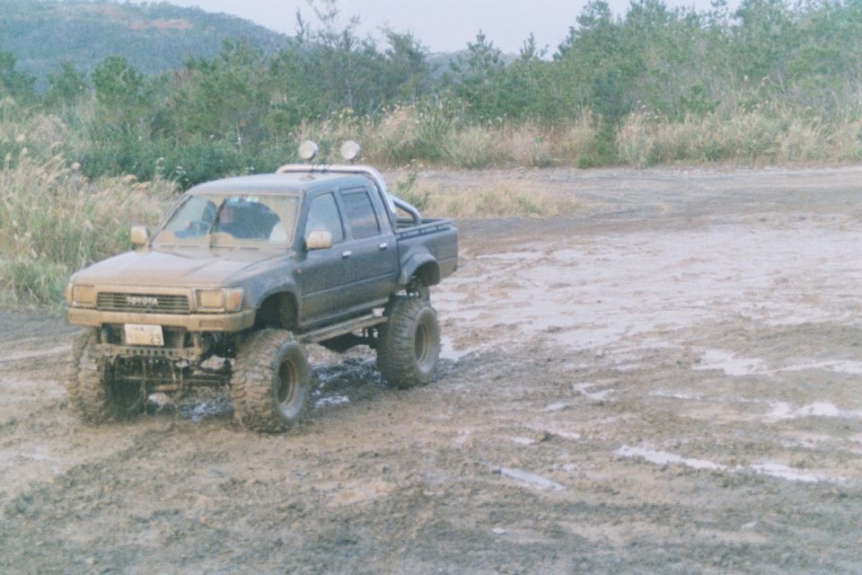 Dark gray Toyota pickup truck with lifted suspension and large tires, parked in mud