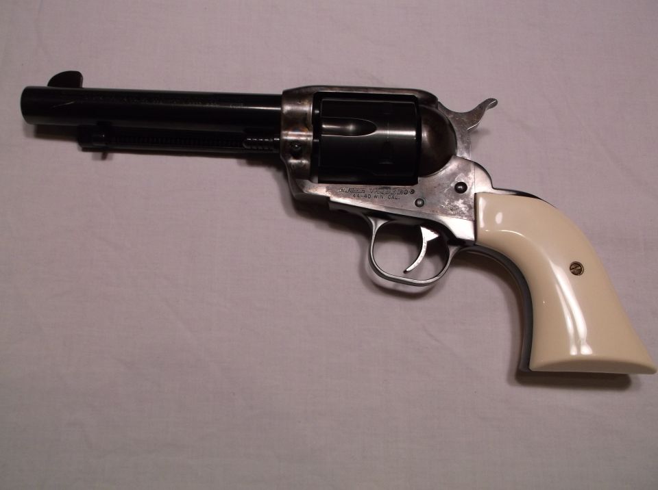 Vintage revolver with black barrel, silver frame, and cream grips.