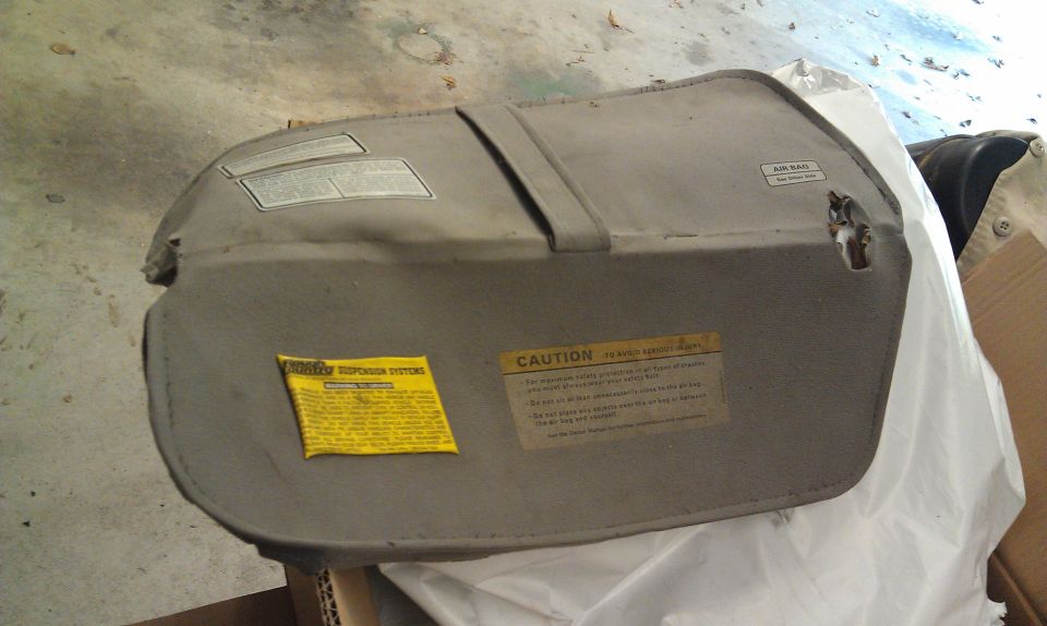 Gray car sun visor with caution and air bag labels.