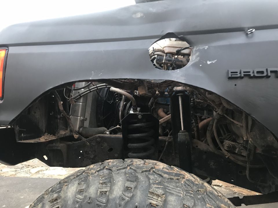 Gray Ford Bronco rear fender well with a circular cutout in the body.