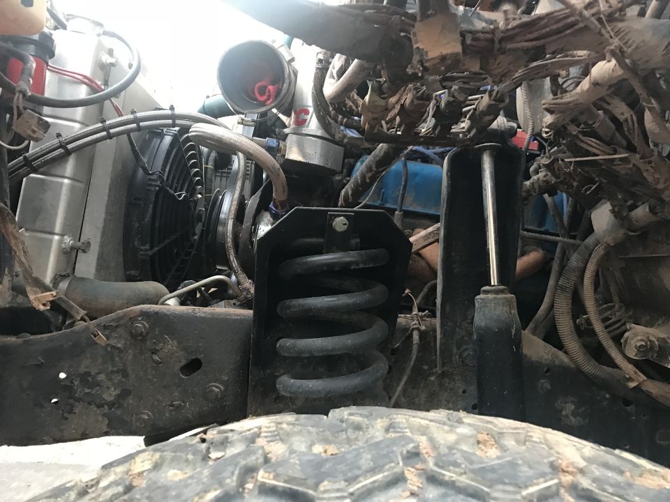 Front suspension and engine bay of a vehicle with a coil spring and shock absorber.