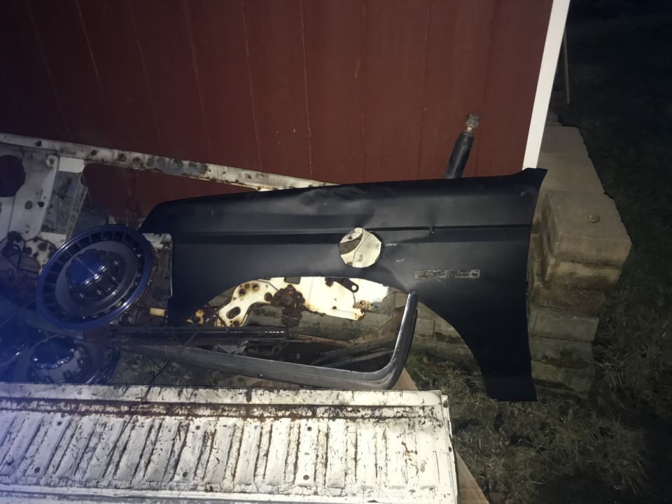 Black fender on a white pickup truck bed, with a hubcap.