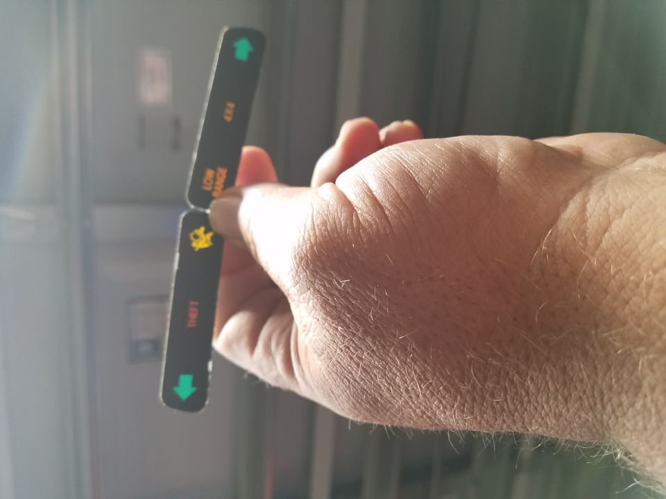 Hand holding a 4x4 low-range indicator lens strip with green arrows