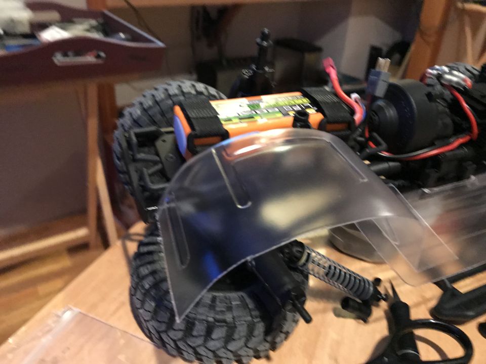 RC car rear wheel, suspension, and battery pack on a wooden surface.