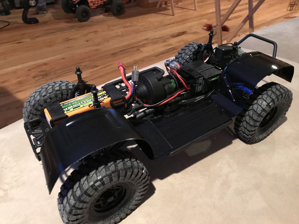 Black remote-controlled off-road vehicle with visible battery pack and large tires.