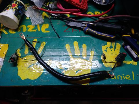 1996 Ford Bronco - A custom alternator wiring harness is laid out on a workbench, surrounded by tools and handprints.