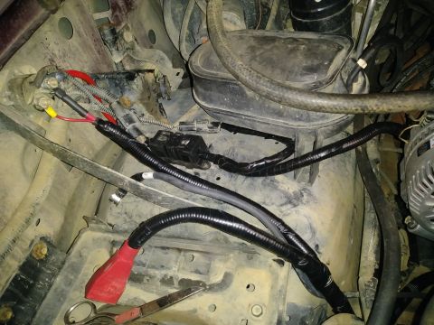 1996 Ford Bronco - Close-up view of engine bay wiring and components, including battery terminals and a portion of the alternator.
