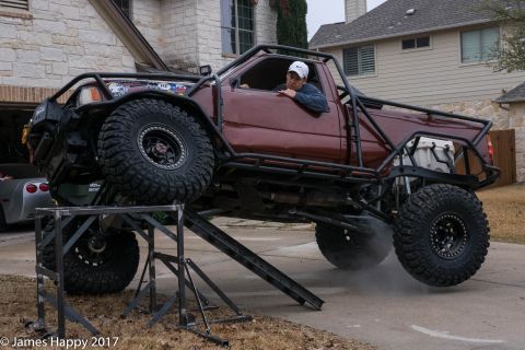 1989 Ford Bronco - A heavily modified pickup truck is positioned on a metal ramp, with one wheel lifted off the ground.