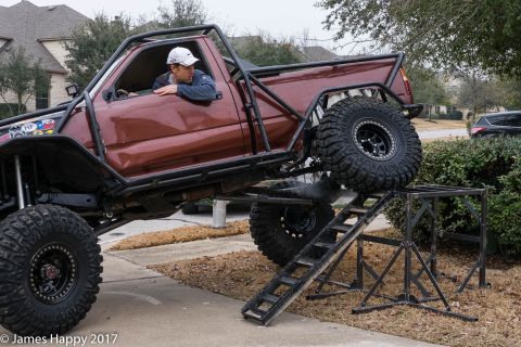 1989 Ford Bronco - A heavily modified pickup truck with a roll cage and oversized tires is positioned on a ramp.