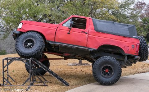 1989 Ford Bronco - This modified SUV is positioned on a metal ramp, its off-road capabilities and large tires.