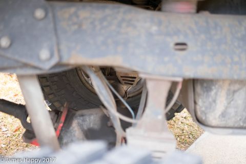 1989 Ford Bronco - A close-up view of a vehicle's undercarriage reveals suspension parts and a tire.